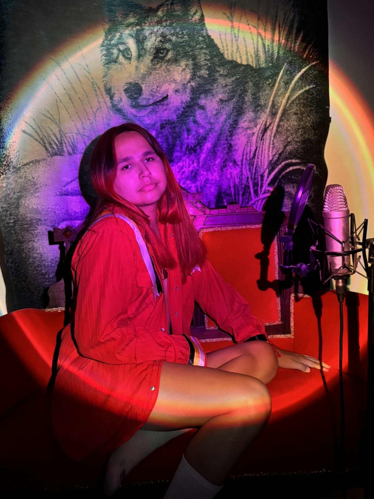 9a in a red shirt on the throne beside a studio microphone
