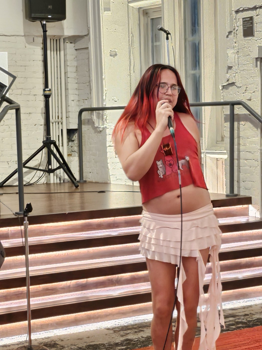 9a singing into a microphone on an outdoor stage